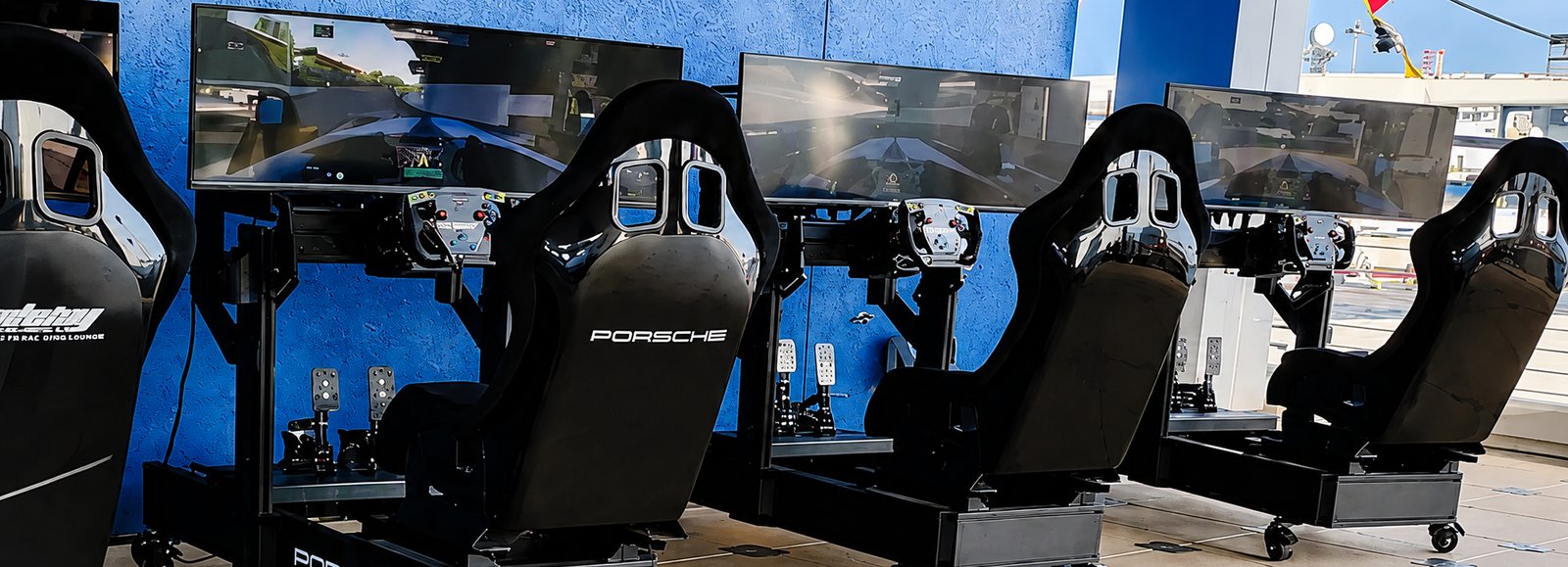 A row of Porsche-branded Academy Sim Racing rigs set up at a rooftop event venue